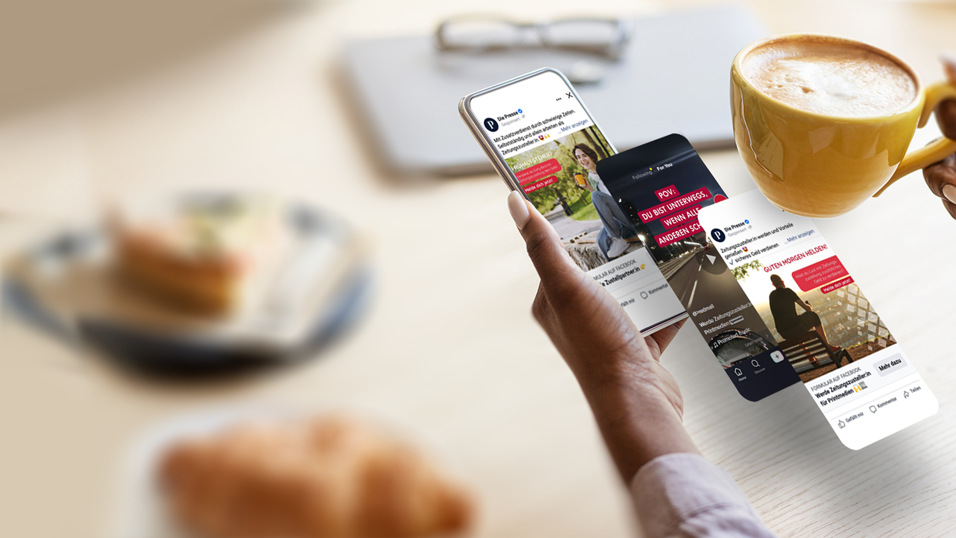 Eine Person hält über einem Tisch mit einem Croissant und einer Tasse Kaffee ein Smartphone, auf denen verschiedene Social-Media-Posts angezeigt werden, die die Wirkung von Performance Marketing veranschaulichen.